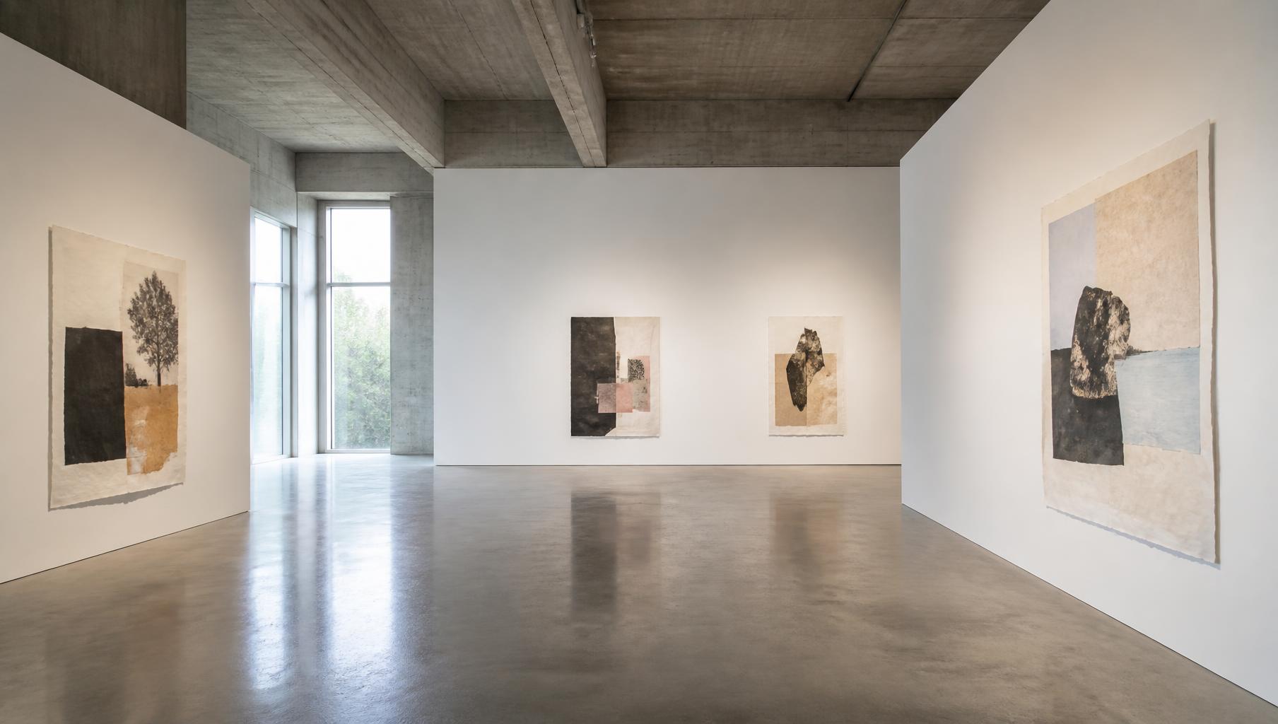Installation view: paper works suspended in a concrete gallery